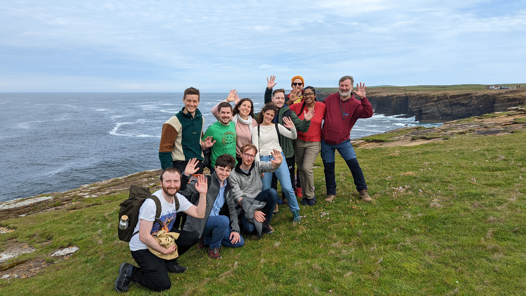 IDCORE group photograph on cliffs above Orkney coastline with sea in background