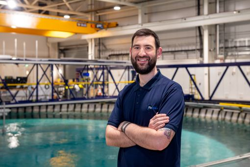 Callum Guy standing arms crossed and smiling within the IDCORE ocean research facility