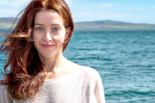 Alyona Naberezhnykh headshot with sea mountains and blue sky in the background