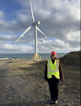 Maria standing in front of a wind turbine