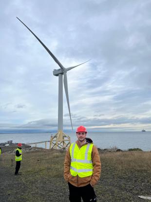 IDCORE Research Engineer - Nikitas Fotiou standing in front of a wind turbine