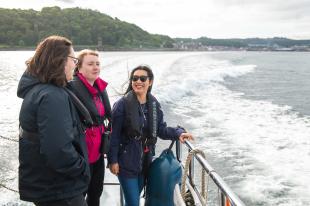 A group of three students on a small boat at sea