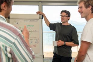 A group of three students chatting around a whiteboard