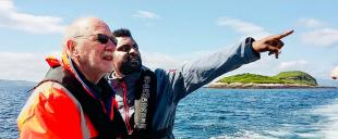 Mujahid Elobeid pointing out to sea beside the captain of the boat