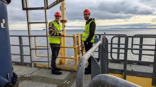 Two IDCORE students standing on a turbine Transitions Piece