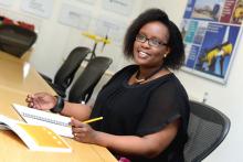 Dr Inès Tunga sitting in an office environment with pen and paper