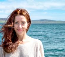 Alyona Naberezhnykh headshot with sea mountains and blue sky in the background